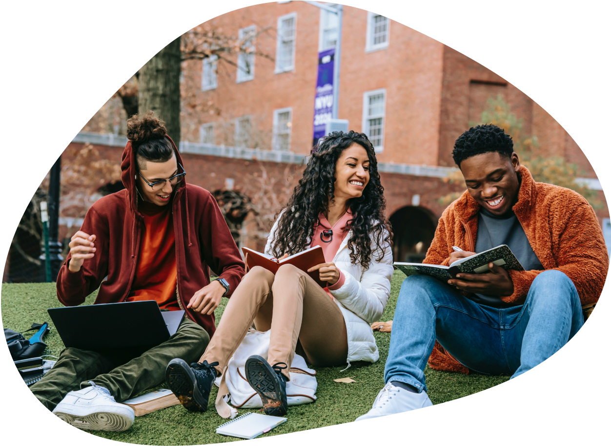 three students sitting on the lawn of a college campus
