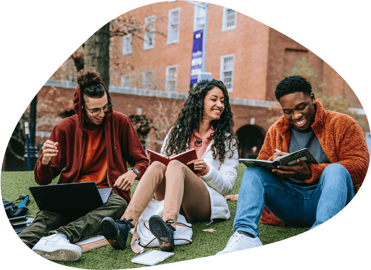 three students sitting on the lawn of a college campus